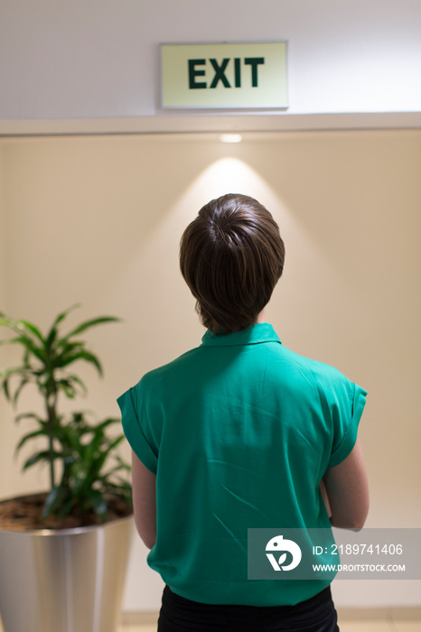 Businesswoman looking up at exit sign