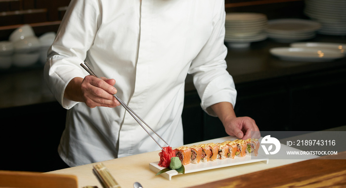 Chef prepares sushi with torch burner. Classic Japanese sushi food served on a stone plate