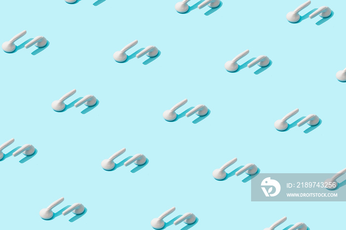 Trendy sunlight Summer pattern made with white earphones on bright light blue background. Minimal su
