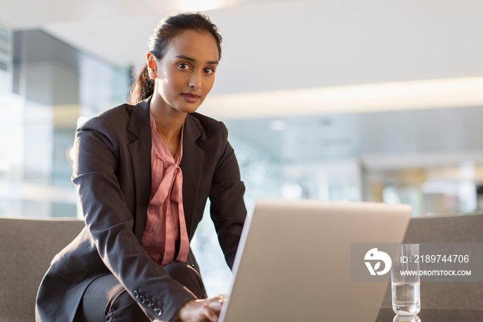 Portrait confident young corporate businesswoman at laptop in office