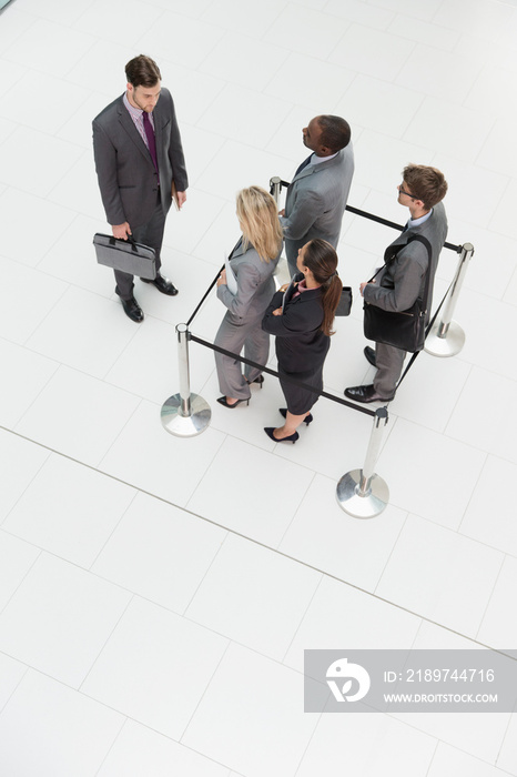 Businessman watching business people trapped in square stanchions