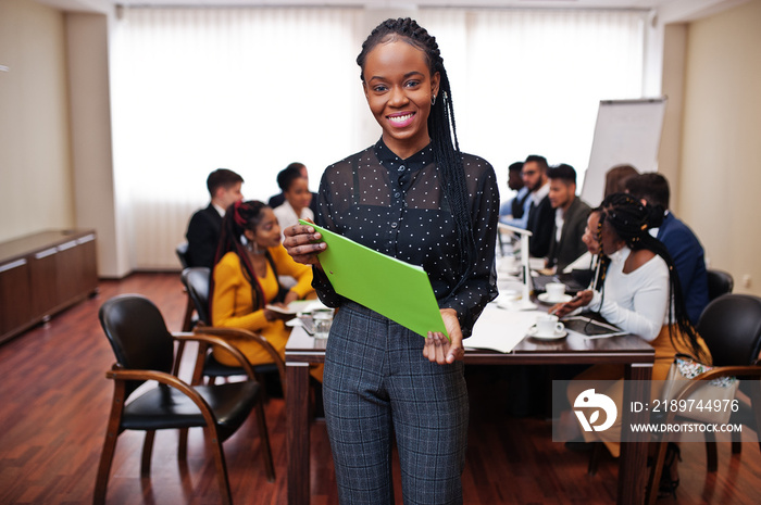 Face of handsome african business woman, holding clipboard on the background of business peoples mul