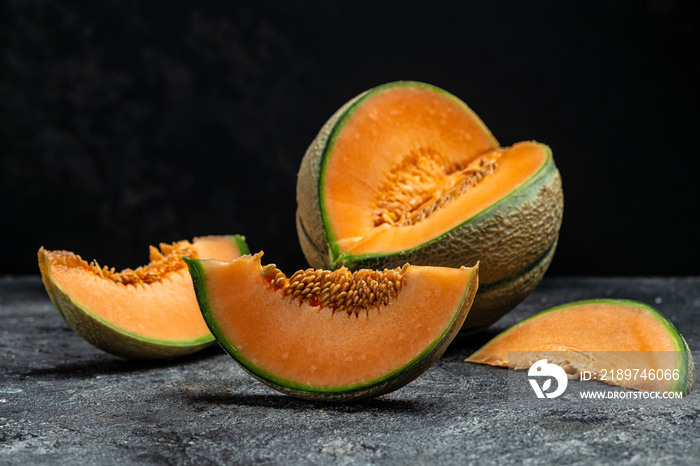 Whole and sliced of Japanese melons or cantaloupe on dark background. place for text