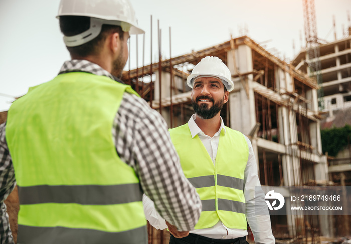 Male builders shaking hands during work