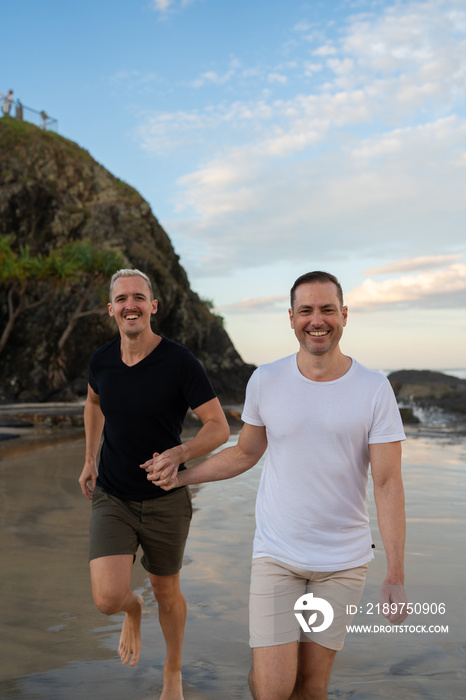 一对同性恋情侣在海滩上牵手奔跑，树和岩石微笑
