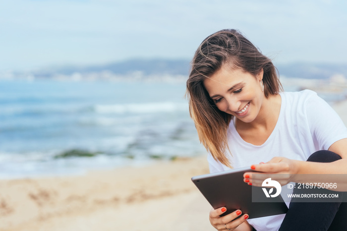 Young woman sitting reading on her tablet pc