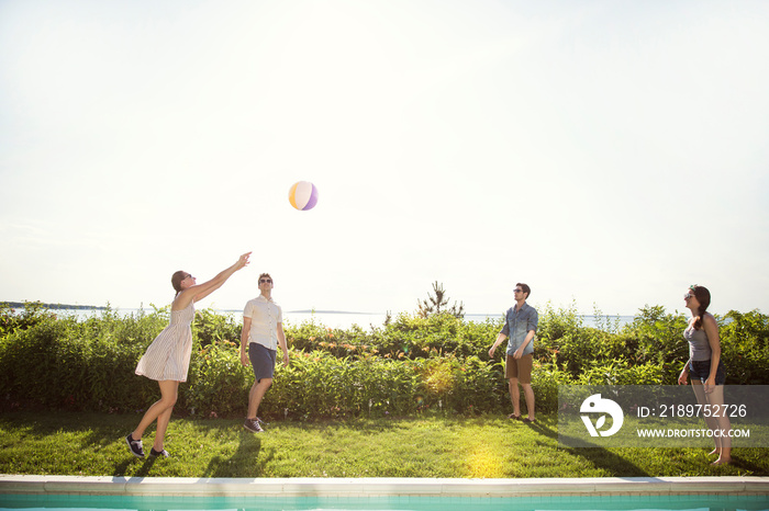 Young people playing volleyball by swimming pool