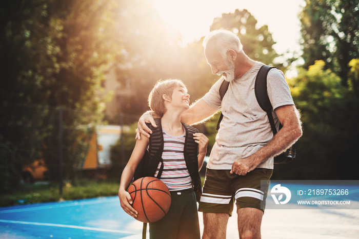 Grandfather and his grandson enjoying together on basketball court.