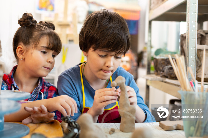 Brother and sister at the art lesson modeling clay animals