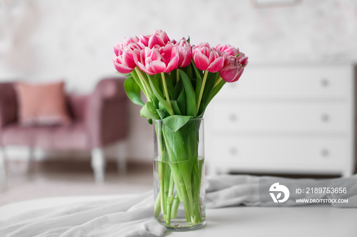 Vase with beautiful tulips on table in light room