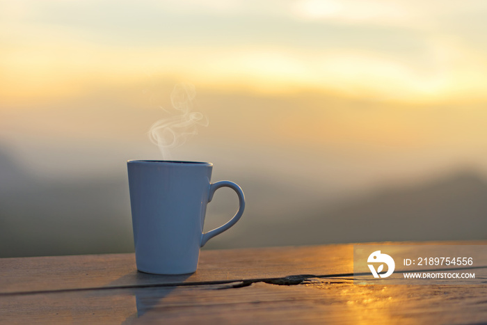 Cup coffee and tea with steam on wood table outdoor over mountains landscape with sunlight. Beauty n