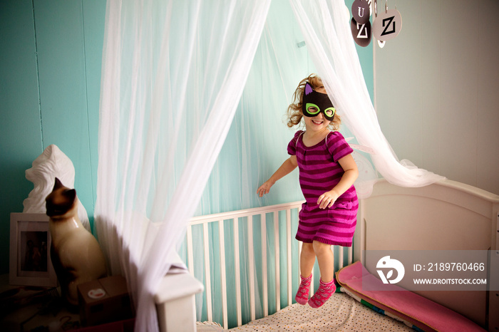 Girl wearing mask jumping on bed