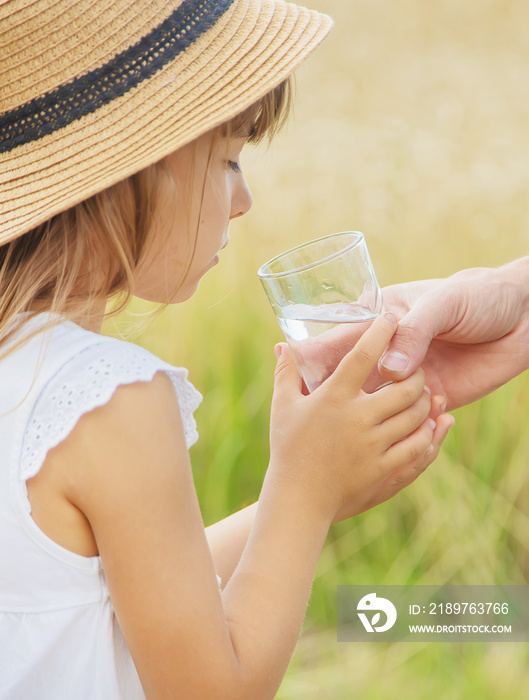 父亲在田地的背景中给孩子喝水。选择性聚焦。