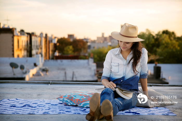 Woman sitting on blanket on rooftop