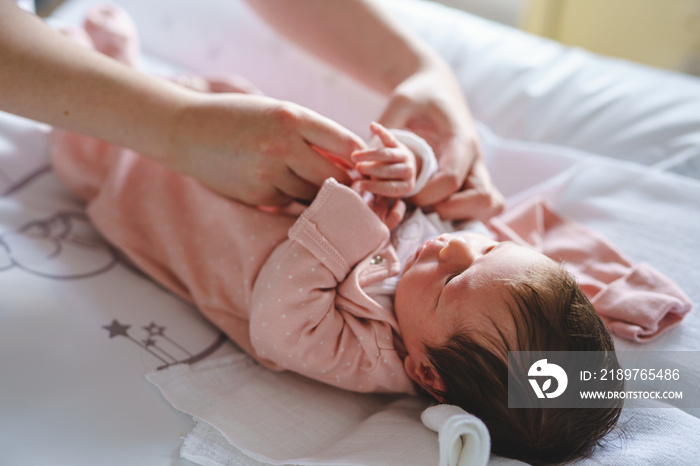 Unknown woman mother taking care of her baby boy or girl putting on clothes - newborn caucasian infa