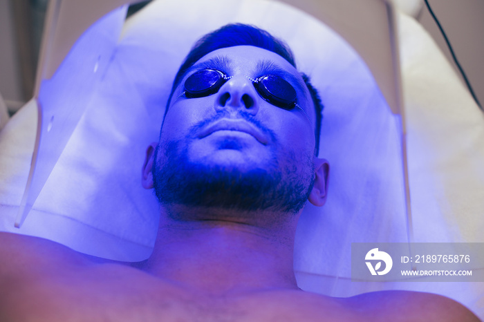 Face of a calm young man lying in tanning bed in solarium