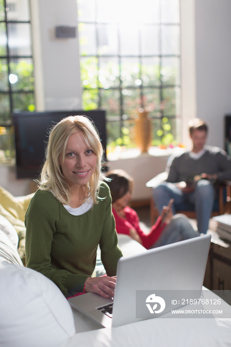 Portrait young woman using laptop on sofa