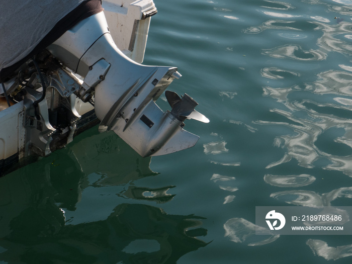 Outboard motor with propellor out of water, on the back of a small boat