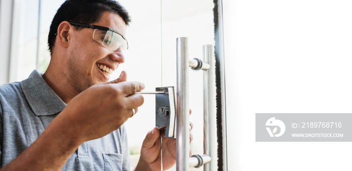 Close-up of male hands repair or installing a metal door lock on glass door.