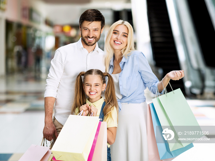 Family Of Three Posing With Shopping Bags In Mall Center