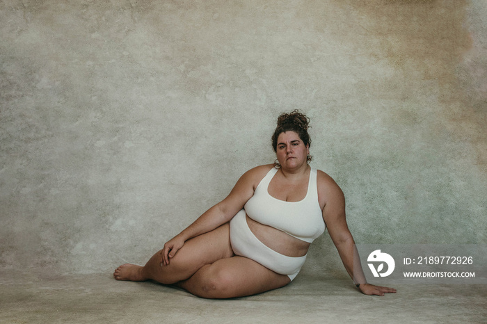 portrait of a plus size woman sitting on hip looking at the camera