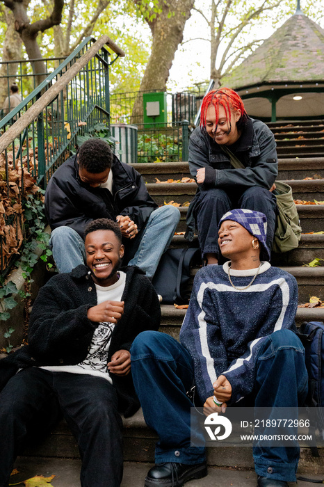 A group of black trans friends sat on the steps talking.