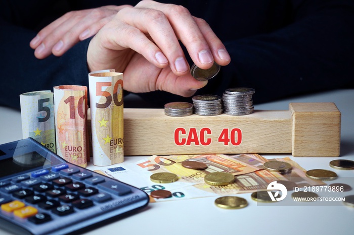 CAC 40. Mann stapelt Geld (Euro). Begriff CAC 40 auf Baustein. Münzen, Scheine & Taschenrechner. Kon