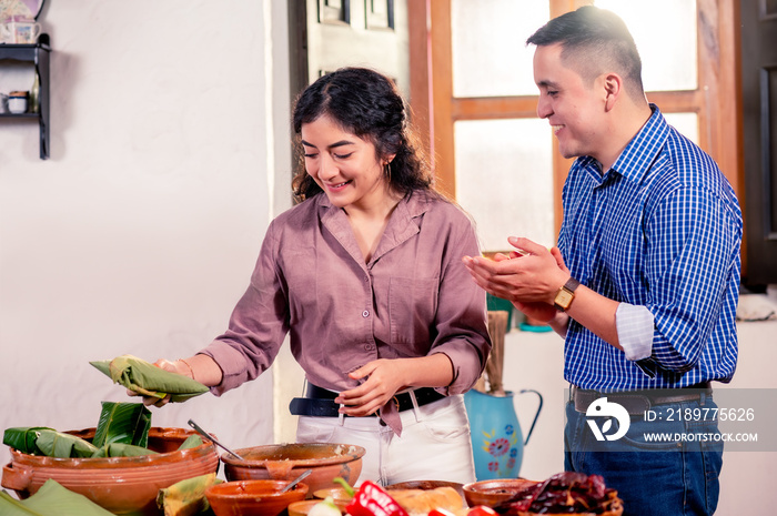 Pareja latina moderna de  marido y mujer  cocinan  juntos tamales para conservar sus tradiciones.