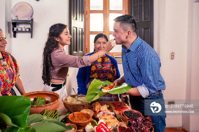 Esposo y esposa cocinando con su madre y su suegra, Pareja latina haciendo tamales.