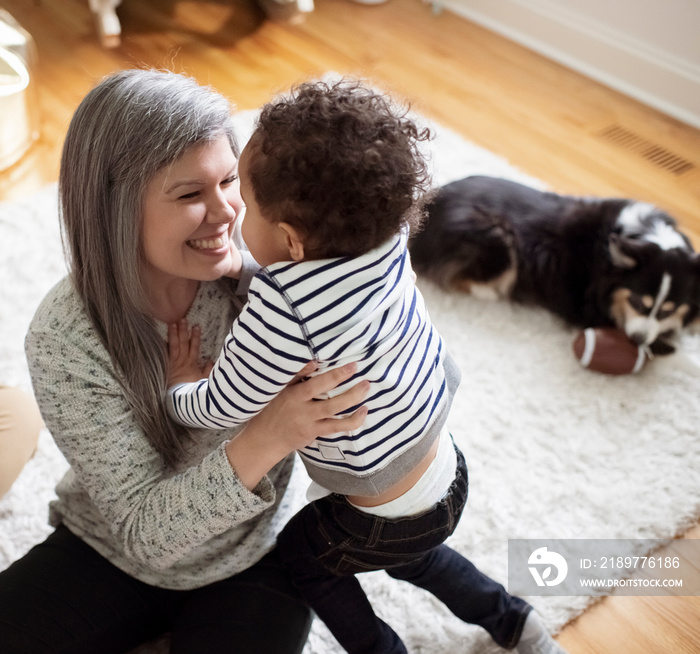 High angle view of father looking at happy mother carrying son while sitting on rug in room