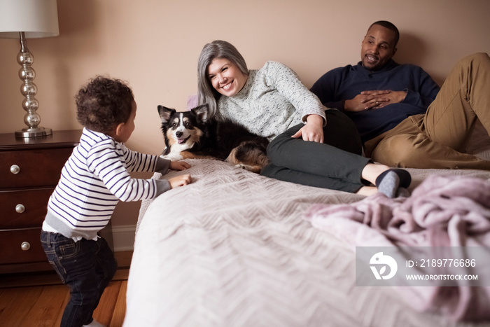 Parents with dog looking at son standing by bed in bedroom