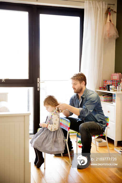 Father doing hair of his daughter at home