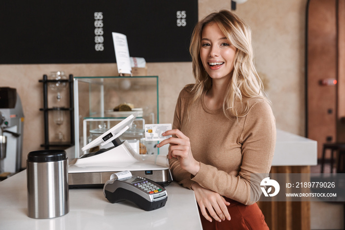 Girl happy excited buyer in cafe standing near terminal holding debit card.