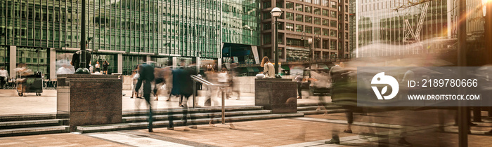 Canary Wharf plaza in central London at sunrise with commuters travelling to work panoramic