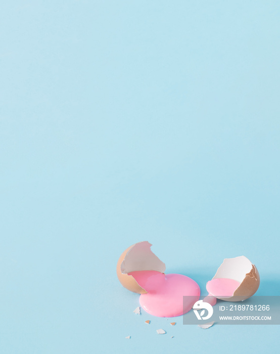 蛋壳与柔和的粉红色油漆。蓝色背景上的创意复制空间。最小的复活节假期conc