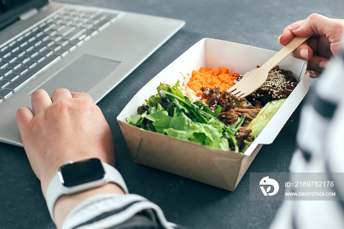 女人用笔记本电脑在回收的碗里吃午饭。送餐、隔离、外卖的概念
