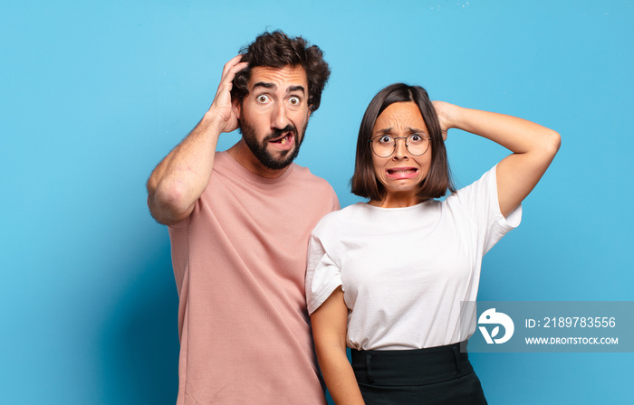 young couple feeling stressed, worried, anxious or scared, with hands on head, panicking at mistake