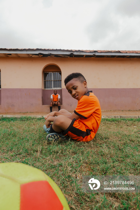 Child sitting on grass while taking a break with Dad