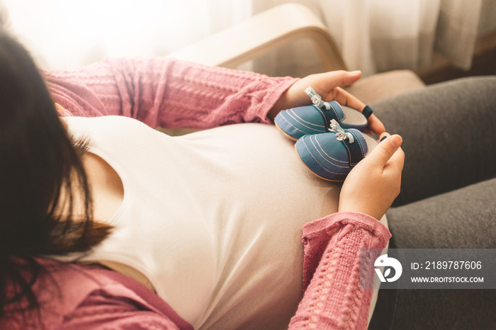 Pregnant woman feeling happy at home while taking care of her child. The young expecting mother hold