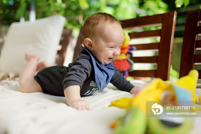 Cute three months old baby boy playing with his toys outdoor. Baby during tummy time. Cute little ch