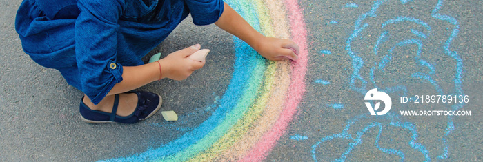 child draws with chalk on the pavement. Selective focus.
