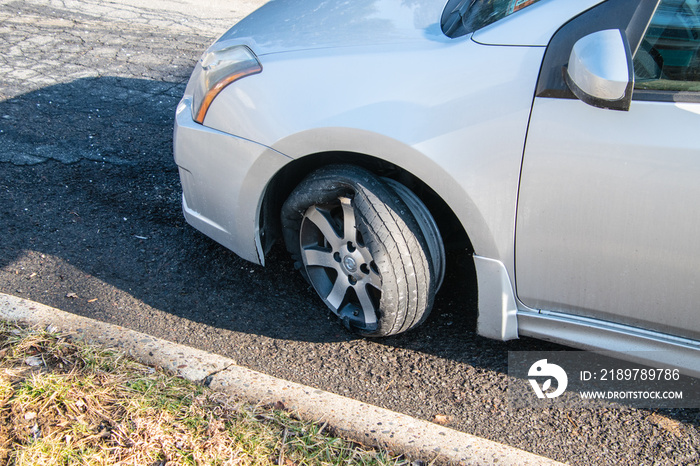 Car tire that has a blowout with rim and car damage