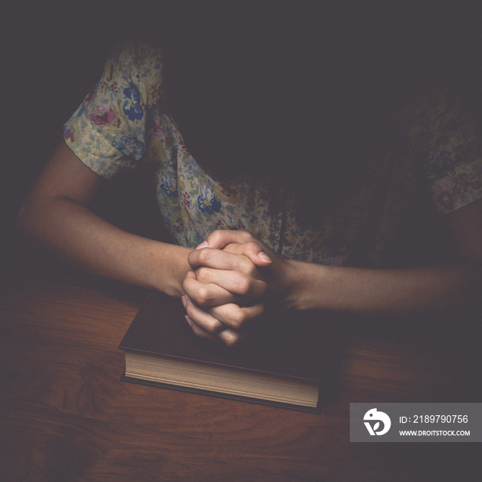 Woman hands praying with a bible, vintage tone