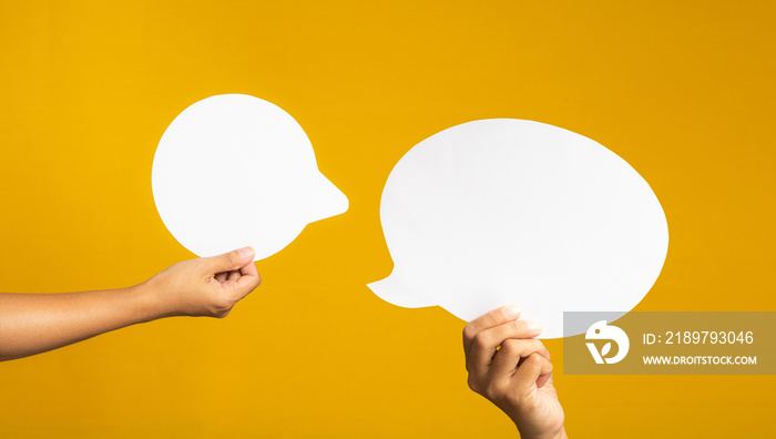 Hand holding of an empty white speech bubble against a yellow background.