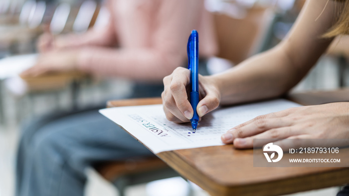 Close up of a young female university student’s hand writing the answer of the examinations on answe