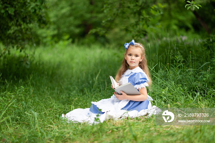 Little cute girl in a costume of  Alice from Wonderland  is reading a book.