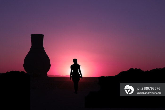 Frau spaziert in der Wüste den Sonnenuntergang entgegen