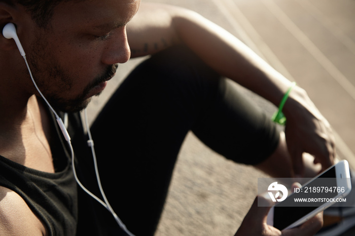 Human and technology concept. People and sport. Handsome African guy in headphones listening to musi