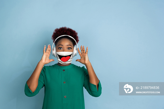 Music listening. Portrait of young girl with emotion on her face mask on studio background. Beautifu