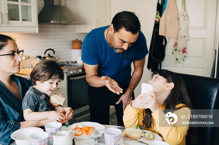 Father asking for smart phone from daughter during breakfast with family